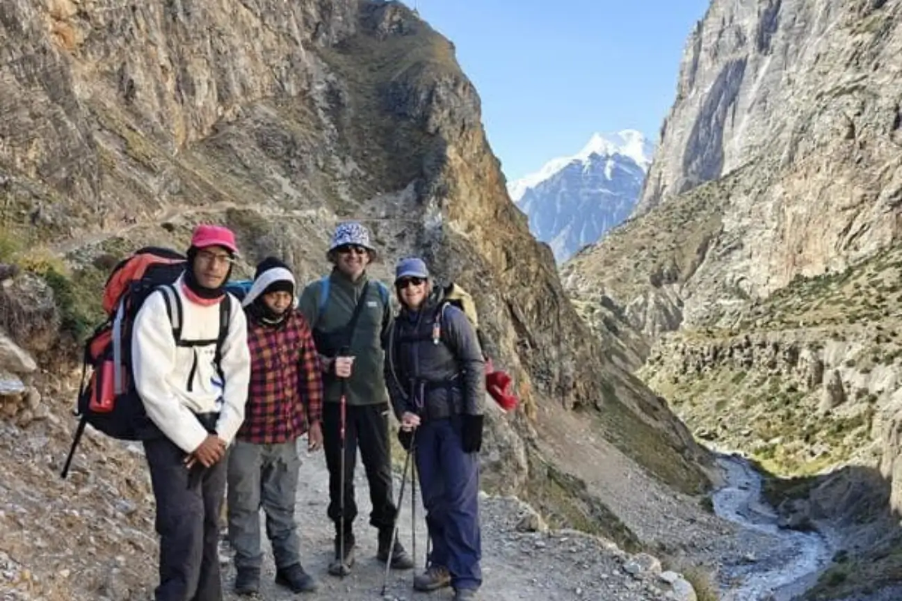 A group of smiling trekkers and local guides posing together along a rocky trail during the Annapurna Circuit Trek Tour.