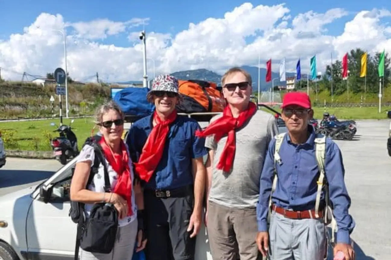 A happy family and tour guide wearing traditional scarves near a vehicle at the start of the Annapurna Circuit Trek Tour.