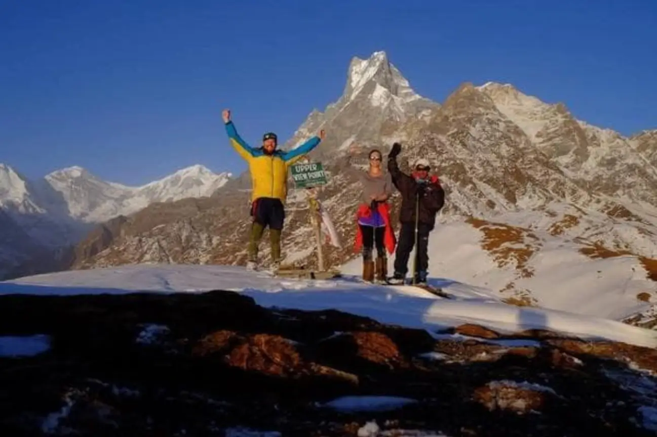 Trekkers celebrating at a snowy high-altitude viewpoint with majestic mountain peaks during the Annapurna Circuit Trek Tour.